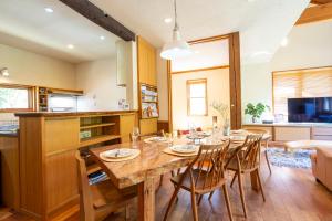 a kitchen and dining room with a wooden table and chairs at CALL92Chalet in Hakuba