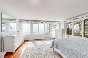 a bedroom with a white bed and windows at Magnolia Tides in Gloucester