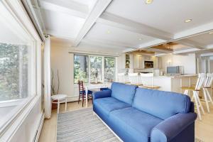 a living room with a blue couch and a kitchen at Magnolia Tides in Gloucester
