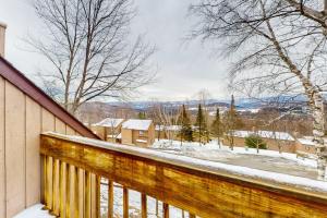 a snow covered balcony with a view of a house at The Summit: 46 in Warren