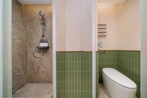 a bathroom with a toilet and a shower with green tiles at Nostalgia S Hotel Beijing Guomao in Beijing
