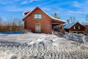 a log cabin with a pile of snow in front of it at The Cabin & Loft Fort Defiance in Pittsfield