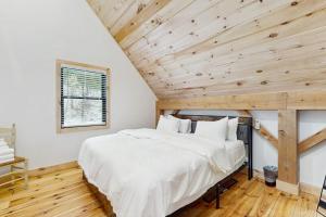 a bed in a room with a wooden ceiling at Timber Riverhouse in Readsboro