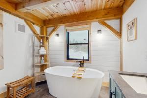 a large white tub in a bathroom with a window at Timber Riverhouse in Readsboro