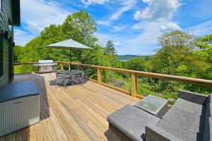 a wooden deck with a table and an umbrella at Timber Riverhouse in Readsboro