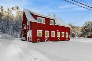 a red barn with snow on the ground at Mill Brook Retreat - Unit 1 in Waitsfield