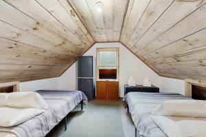 two beds in a room with a wooden ceiling at Brook Haven Cabin in Jeffersonville