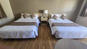 a hotel room with two beds and a table at Gateway Motel in Minnedosa