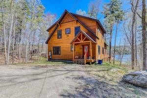 a large wooden cabin in the woods with a driveway at Lake Rescue Retreat in Ludlow