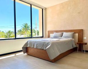 a bedroom with a bed and a large window at Villa con rooftop para atardeceres in Telchac Puerto