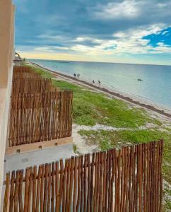 a wooden fence next to a beach with the ocean at Private villa among palms in Telchac in Telchac Puerto