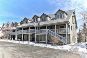 a large house with a porch in the snow at Solitude Village H103 in Ludlow
