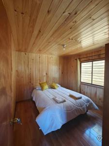 a bedroom with a large bed in a wooden room at Cabaña Queule Costero in Queule