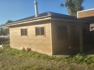 a small house with a black roof on a yard at Cabaña Queule Costero in Queule