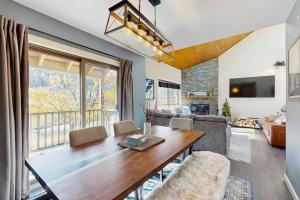 a living room with a wooden table and a large window at Trail Creek 60 in Killington