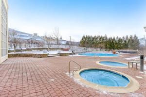 two swimming pools on a brick courtyard with a building at Long Trail House 368 in Stratton