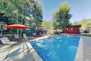 a swimming pool with chairs and umbrellas and a building at Gore Creek Getaway in Vail