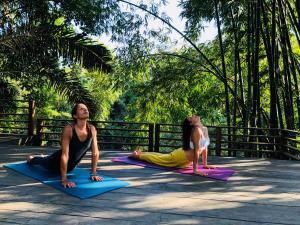 two women sitting in a yoga pose in front of a fence at Villa Palem in Tabanan
