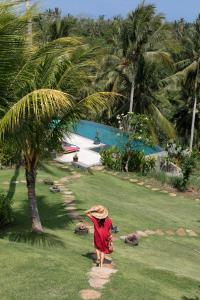 a woman walking down a path near a palm tree at Villa Palem in Tabanan