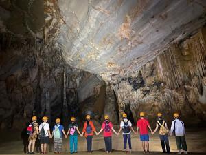 a group of people standing in front of a cave at Gold Plus hotel in Phong Nha