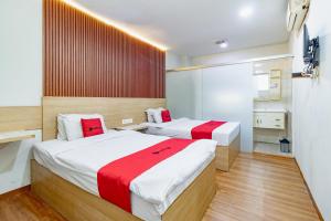 a bedroom with two beds with red and white sheets at RedDoorz Plus at Suba Hotel Tanjung Duren in Jakarta