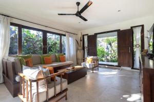 a living room with a couch and a ceiling fan at Villa Nesanur - Comfortable & Spacious Beachside Sanur in Sanur