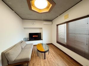 a living room with a couch and a glass table at Goryokaku rental house SAKURA in Hakodate