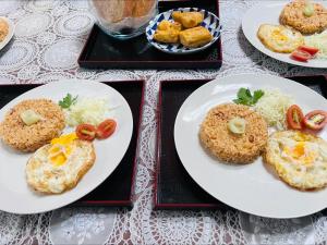 two plates of food with eggs and tomatoes on them at Spacious 3BR Villa Near Kaliurang - Arfani's House in Ngaglik +17 photos