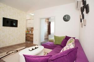 a living room with a purple couch and a tv at B&T Apartments in Budva