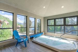 a room with a hot tub with a blue chair and windows at Angelhaus #300 in Durango Mountain Resort