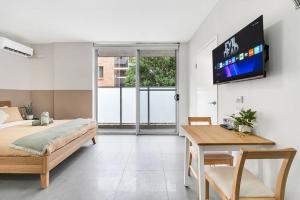 a bedroom with a bed and a tv on a wall at 4B Relaxing Abnb Studio With Balcony, Near Marketplace And Train in Bankstown +26 photos
