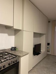 a kitchen with white cabinets and a stove and a tv at Monoambiente céntrico in Gualeguaychú