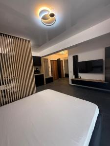 a bedroom with a white bed and a flat screen tv at Luxury & Spacious Studio - Navodari in Năvodari