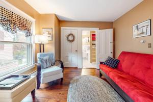 a living room with a red couch and a window at Pied-A-Terre in Kennebunkport
