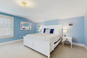 a bedroom with a white bed and blue walls at Quaint Bungalow in Kennebunk