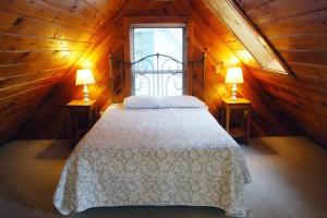 a bedroom with a bed in a wooden cabin with two lamps at Loons Nest Cottage in Standish