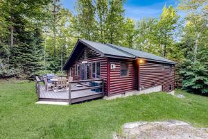 a log cabin with a deck in the grass at Sunday River Sunny Chalet in Bethel