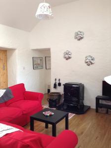 a living room with a red couch and a tv at Hillside Cottage Achill in Achill Sound