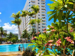 a resort pool with palm trees and a tall building at View Talay 1B Studio in Pattaya South