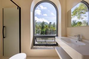 an arched window in a bathroom with a tub and a sink at Nanxiang Shushan Hotel in Sanya +72 photos
