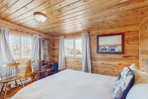 a log cabin bedroom with a bed and two chairs at Grand Lake Cabin Escape in Grand Lake