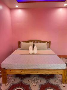 a bed in a room with a pink wall at Tellos Beach House in Siquijor +3 photos