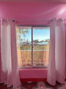 a purple room with a window with a view of the ocean at Tellos Beach House in Siquijor