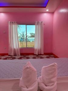 a bedroom with pink walls and a large window at Tellos Beach House in Siquijor