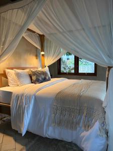 a bedroom with a large white bed with a canopy at First Light Villa at Lipah Beach, Amed in Amed