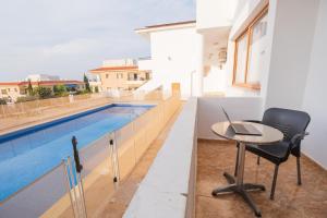 a table with a laptop on it next to a swimming pool at Sunset Sea View Retreat with pool in Kissonerga +2 photos