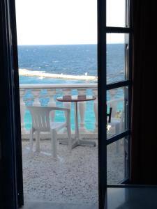 a table and chairs on the beach viewed from a window at Anthemis Rooms in Kokkari