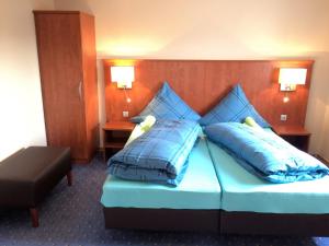 a hotel room with a bed with blue pillows at Hotel - Restaurant Braustube in Haaren