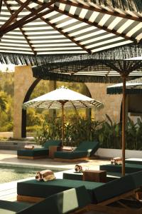 a pool with chairs and umbrellas next to a pool at Kanalla Boutique Hotel - Adults Only in Kuta Lombok +109 photos
