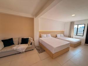 a bedroom with two beds and a couch at RA Suites in Tijuana